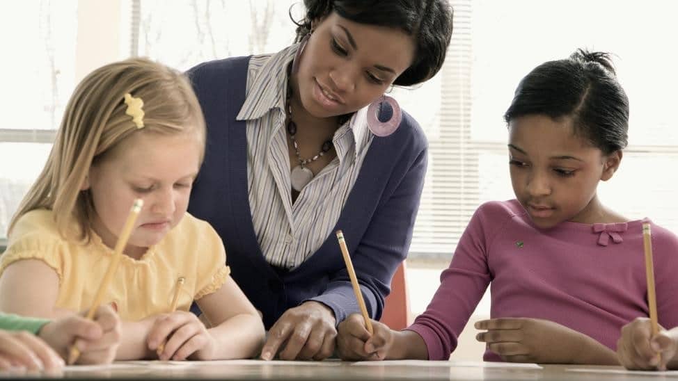 Teacher of color working with two students