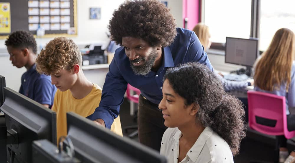 Black male teacher working with students in a computer lab