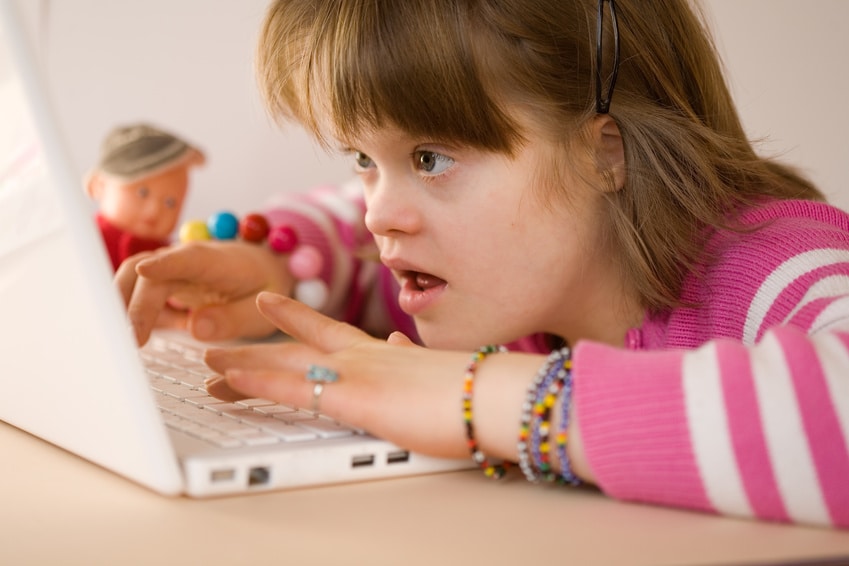 A girl with disabilities using a laptop for a school lesson