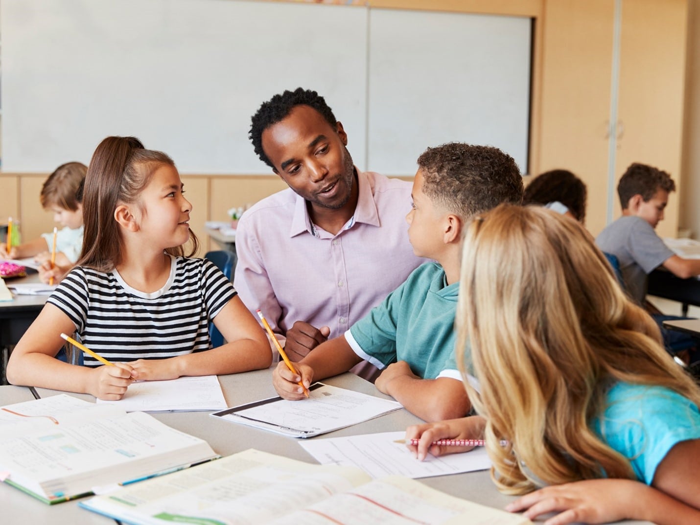 Black male teacher working with students in the classroom