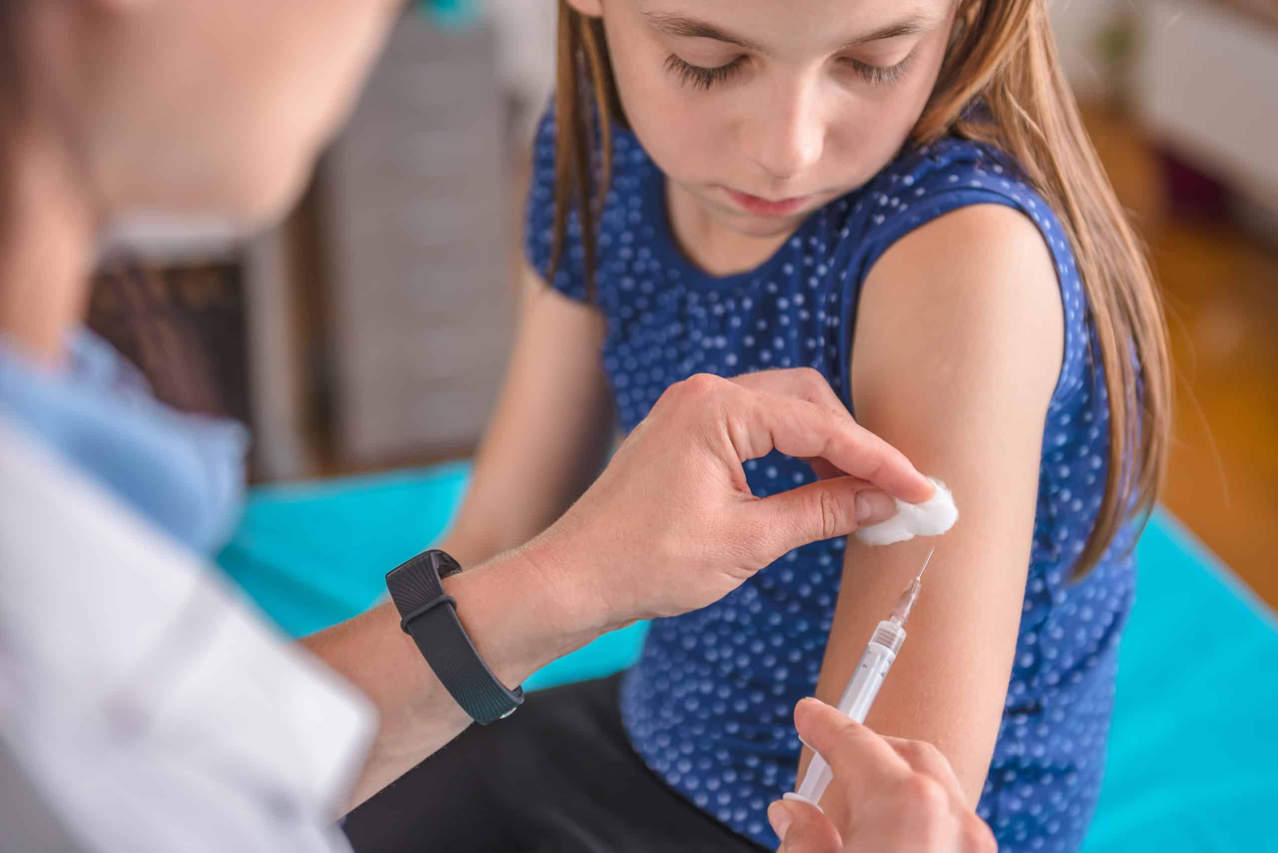 Pediatrics female doctor giving a young girl a vaccine shot in the arm