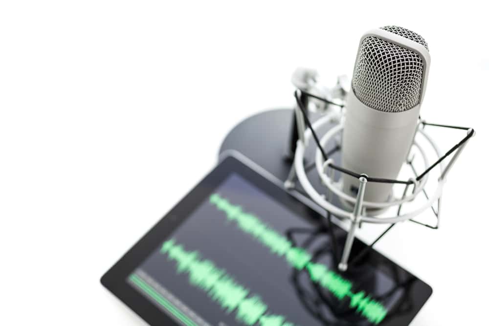 Studio microphone for recording podcasts and computer tablet on a white background.