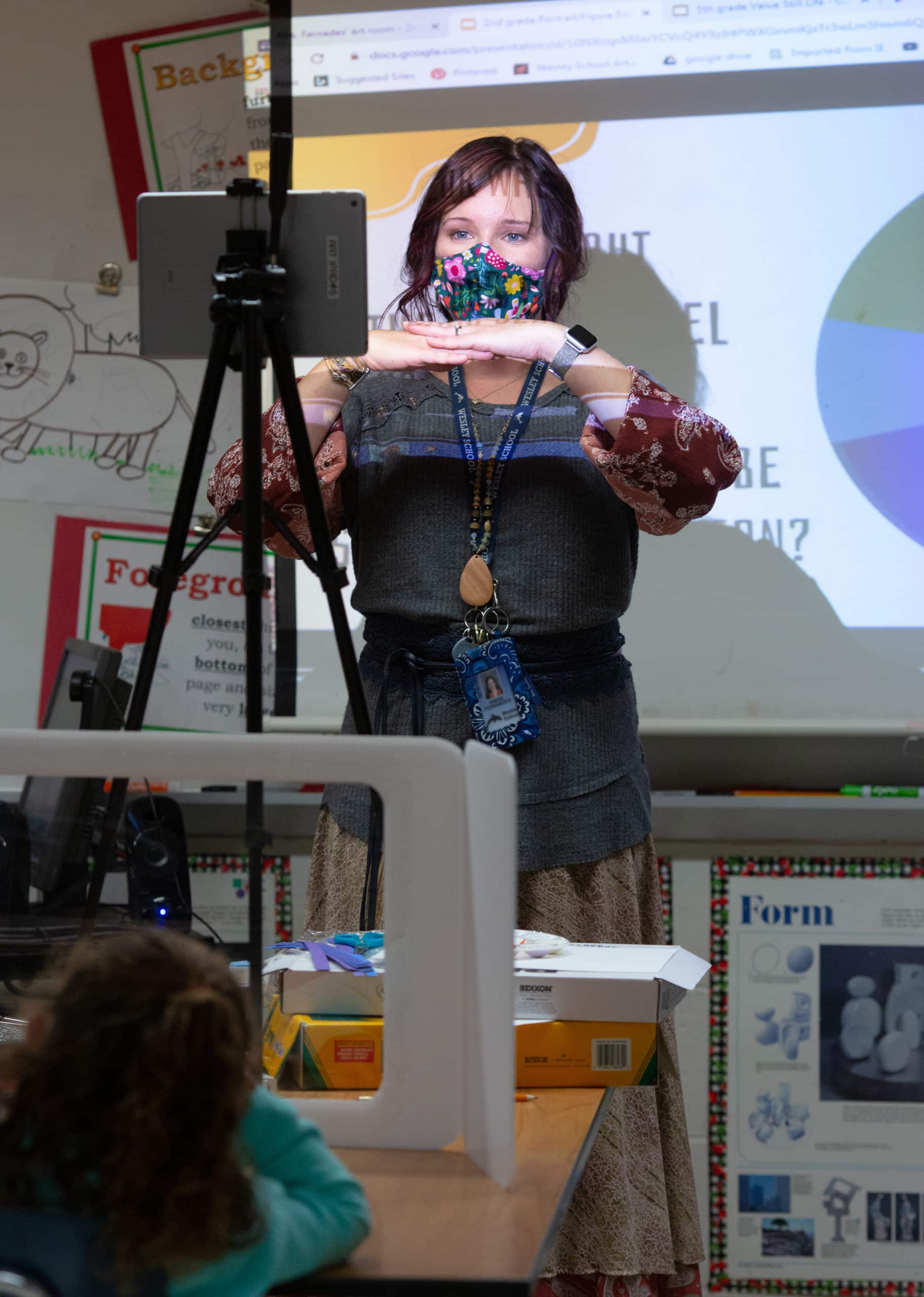 An elementary art teacher instructs second-grade students attending in person and remotely at Wesley Elementary School.