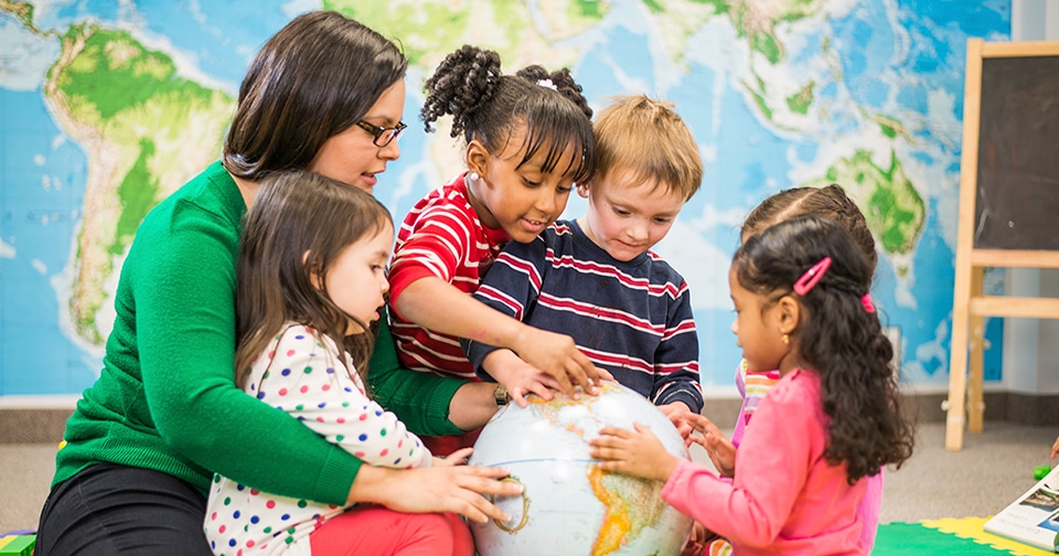 Early Childhood teacher with group of students exploring a globe