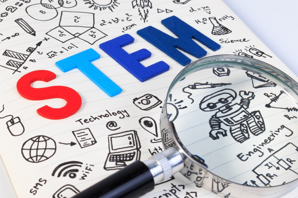 STEM education. Science Technology Engineering Mathematics. STEM concept with drawing background. Magnifying glass over education background.